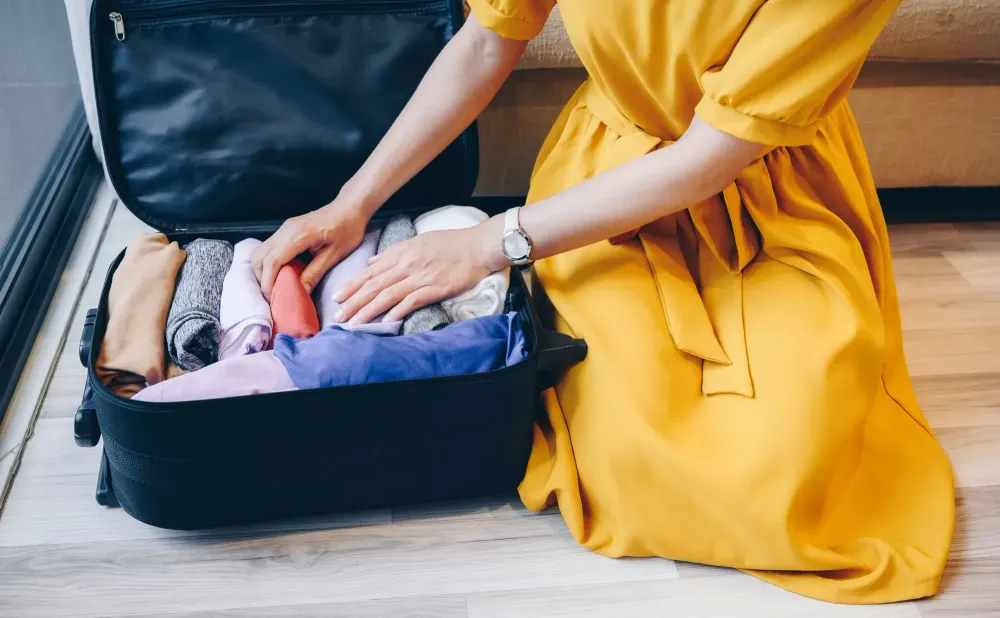 Close up of person in yellow dress packing a suitcase
